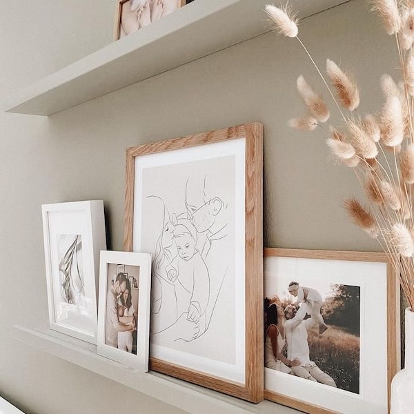 Mur de photos de famille, avec un dessin en Line Art d'une jeune famille, post Instagram de @adriane